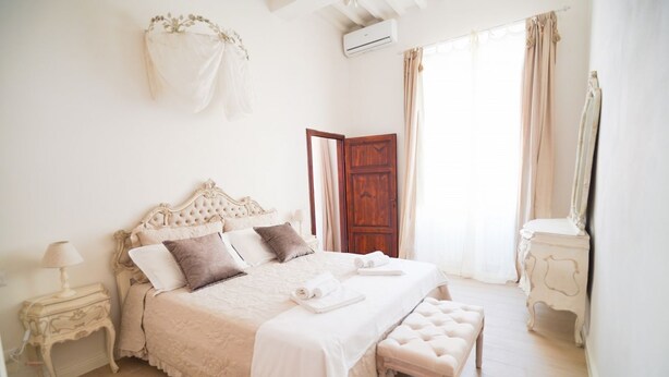 A bedroom with a large bed, a wooden door, a bedside table with a lamp, and a mirror. - Casa Santa Pietra, charming flat in Pietrasanta's center (Pietrasanta)