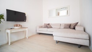 A living room with a sofa, a TV, a console table, and a mirror. - Casa Santa Pietra, charming flat in Pietrasanta's center (Pietrasanta)