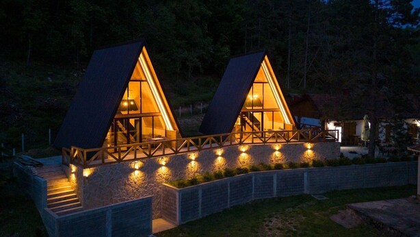 Two triangular-roofed cabins with a stone pathway leading to them, surrounded by trees. - A frame cabins in the heart of a national park! (Rakovac)
