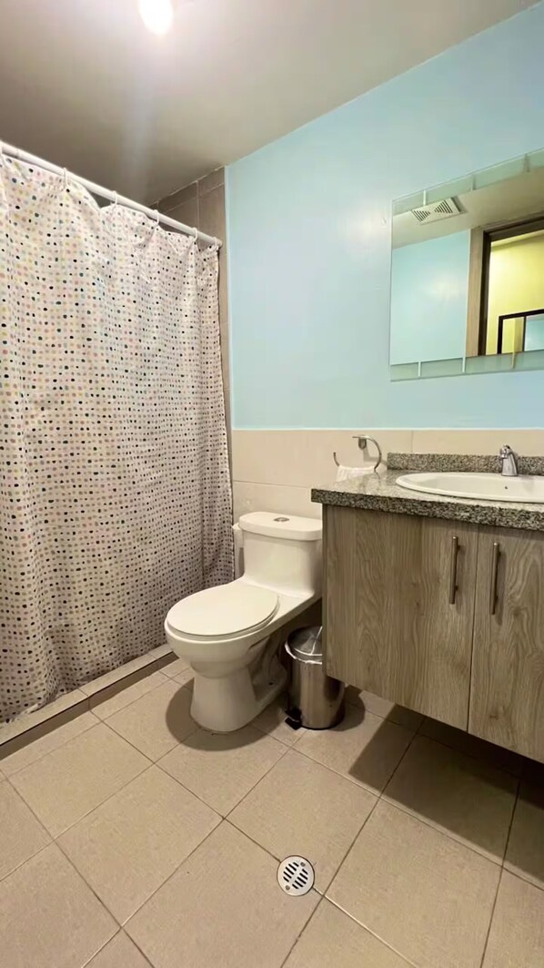 A bathroom with a toilet, sink, and shower curtain. - Comfortable apartment for 8 people, North of Quito, close to Solca and US embassy. (Quito)