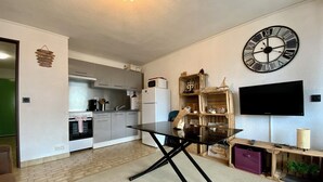 Una cocina moderna con una mesa de comedor, un reloj de pared grande y un televisor de pantalla plana.