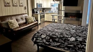 Un espace de vie compact comprenant un coin cuisine, un canapé, un lit et un téléviseur fixé au mur.