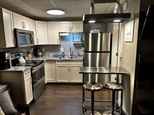 Una cocina moderna con electrodomésticos de acero inoxidable, un lavamanos doble y un taburete de bar.