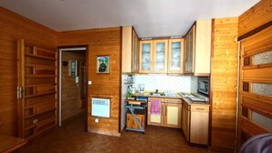 A compact kitchen with wooden cabinets, a microwave, and a small dining area. - Canet-en-Roussillon T2 Beachfront with Parking - Perfect for 4 (Canet-en-Roussillon)