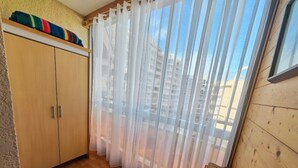 A room with a wooden wardrobe, a window with sheer curtains, and a view of buildings outside. - Canet-en-Roussillon T2 Beachfront with Parking - Perfect for 4 (Canet-en-Roussillon)