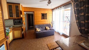 A compact living space with a kitchenette, a ceiling fan, a sofa, and a dining table. - Canet-en-Roussillon T2 Beachfront with Parking - Perfect for 4 (Canet-en-Roussillon)