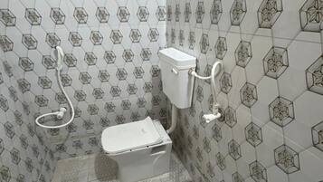 Een badkamer met tegels in een honingraatpatroon, een toilet en een douchehoek.