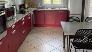 Ett modernt kök med röda skåp, en rostfri köksfläkt, en inbyggd ugn och ett fönster ovanför diskbänken.