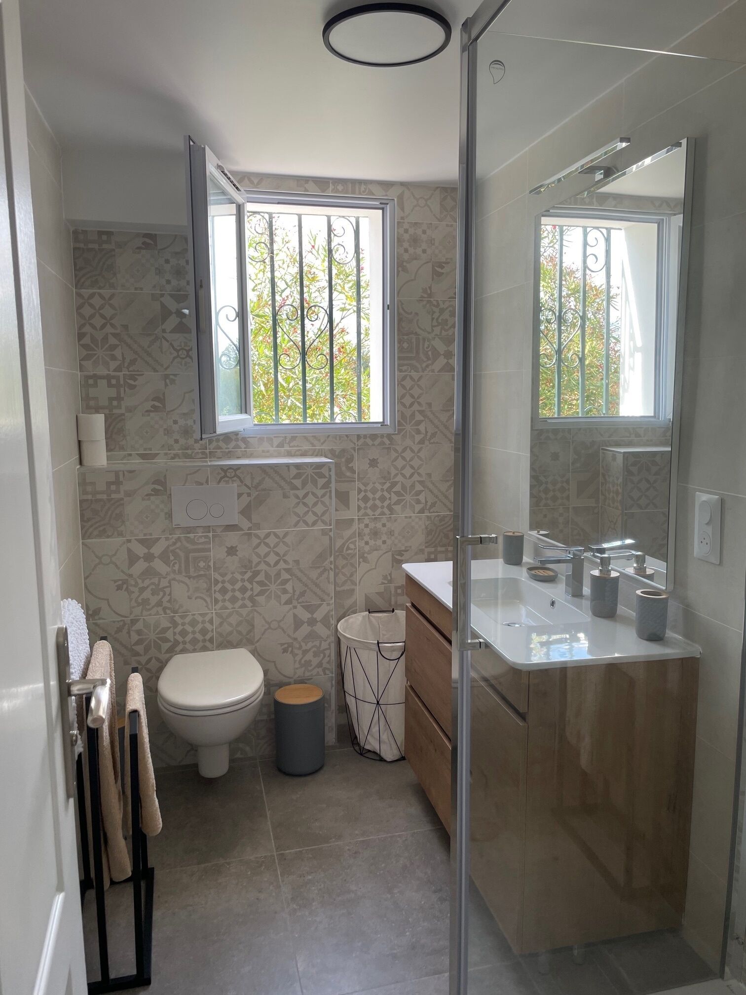 A modern bathroom with a toilet, bidet, sink, and mirror.