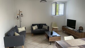 Ett modernt vardagsrum med en soffa, ett soffbord, en tv och en matplats med ett bord och stolar.