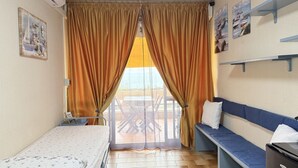 Ein Hotelzimmer mit Bett, einer Couch, einem Schreibtisch und einem Balkon mit Tisch und Stühlen.