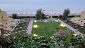 Eine angelegte Grünfläche mit Pool, Blick auf den Strand und einem Weg zum Strand.