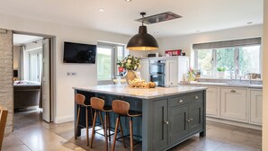 A modern kitchen with a large island, bar stools, and a pendant light. - Luxury Countryside Retreat with Pool | Surrey Hills Escape - Pass the Keys (Leatherhead)