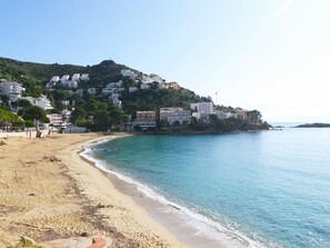 A coastal beach with buildings on a hillside, clear skies, and calm sea. - Spacious apartment in Roses - Quiet area for 5 (Roses)