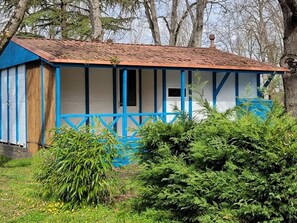 Un petit bâtiment d’un seul étage, à la façade bleue et blanche, entouré de verdure.