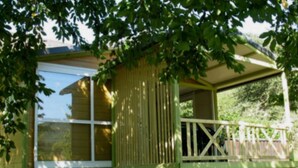 A small, single-story wooden structure with a balcony, surrounded by lush greenery. - Comfortable 2-Bedroom Chalet with Terrace in Vébron (Vebron)