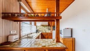 A kitchen with wooden cabinets, a tiled backsplash, and a built-in oven. - 3-Bed House 100m from Beach (Biscarrosse)