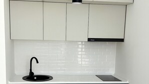 Une cuisine de taille réduite avec des meubles de couleur turquoise, un plan de travail blanc et un robinet noir.