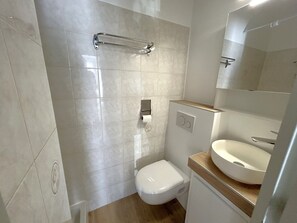 A modern bathroom with a toilet, a sink, and a shower area. - Air-Conditioned Apartment for 4, 50m from Beach (Argelès-sur-Mer)