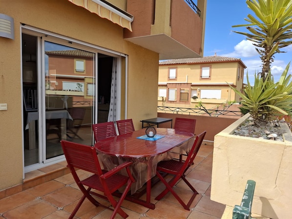 A patio with a table and chairs, a sliding glass door, and a small plant.