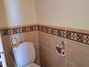 A bathroom with a toilet, a hand dryer, and a paper towel dispenser. - Valras-Plage: Duplex 2BR with Pool, AC, Terrace (Valras-Plage)