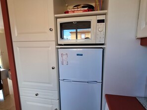 A compact kitchen with a white microwave and a white refrigerator. - Valras-Plage: Duplex 2BR with Pool, AC, Terrace (Valras-Plage)
