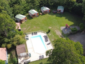 An aerial view of a residential area with a swimming pool, several houses, and a playground.