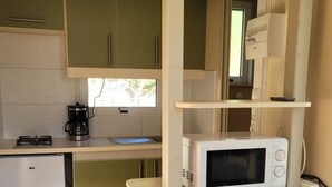 A compact kitchen with a gas stove, a coffee maker, a microwave, and a small refrigerator. - Cozy Chalet with Terrace - Sleeps 5 (Pamiers)