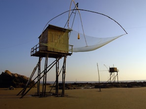 Ein Strand mit Holzbauten, darunter ein Aussichtsturm und ein kleines Gebäude, verbunden durch Treppen.