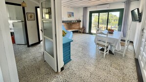 Un'ampia zona giorno con un divano blu, un tavolo da pranzo con sedie, un camino e una grande finestra con vista sull'esterno.