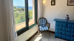 Una stanza con una grande finestra, una sedia in vimini e un comò blu.