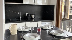 A modern kitchen with a black countertop, white cabinets, and a window with a view of buildings.