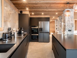 Eine moderne Küche mit dunklen Schränken, einer zentralen Kochinsel und einer Wand mit Steinverkleidung.