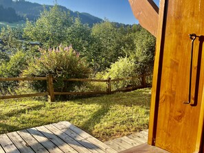 Eine Holzterrasse mit Blick auf eine bewaldete Landschaft und Berge im Hintergrund.