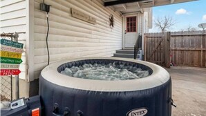 Un bain à remous situé à l’extérieur d’une maison, avec une pancarte indiquant : « Bienvenue sur notre agréable terrasse. »