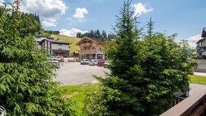 A hotel with a parking lot, surrounded by greenery and a clear sky. - Cozy apartment in Les Gets with parking - sleeps 5 (Les Gets)