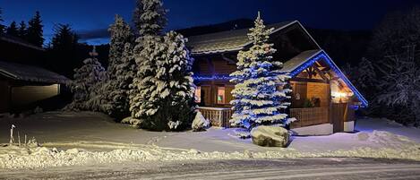 A snow-covered lodge with a wooden exterior and blue exterior lights.