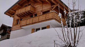 Un chalet en bois doté d’un balcon, entouré de neige.