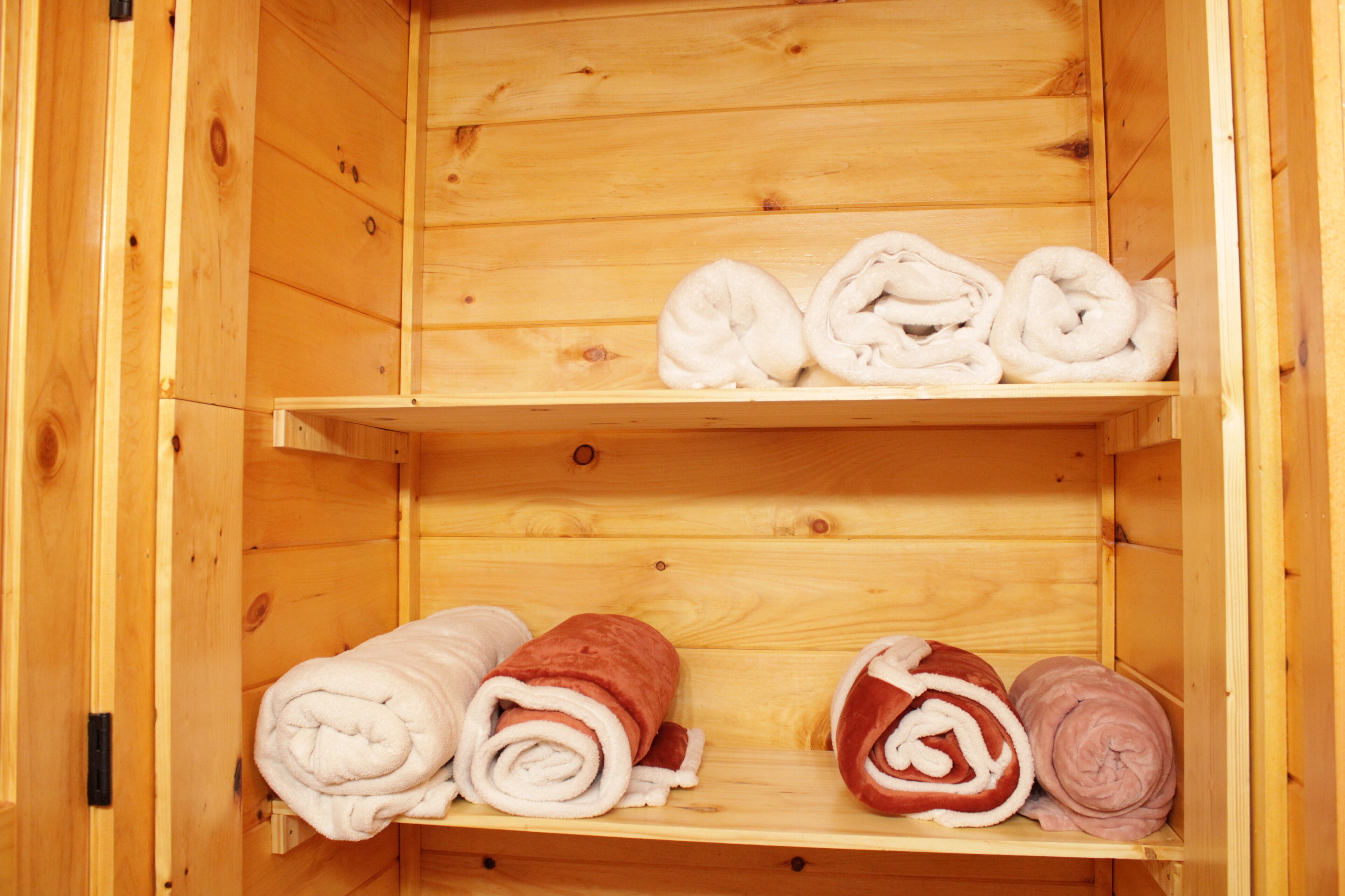 Een houten blokhut met twee planken, elk met opgerolde handdoeken in wit, rood en roze.