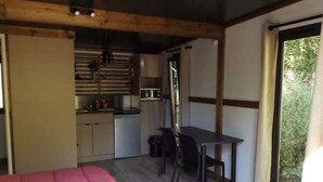 Ein kleines Zimmer mit Bett, einer kleinen Küchenzeile und einem Essbereich.