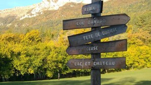 Ein hölzernes Wegweiser mit Pfeilen, die zu verschiedenen Zielen wie 'PIC DE CHARRANCE', 'COL BAYARD', 'TETE DE GUIZIERE', 'CEUSE' und 'LAC ET CHATEAU' zeigen.
