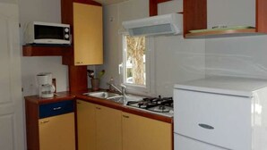 A compact kitchen with a microwave, stove, and sink. - Cozy Mobile Home for 4 with Terrace (Tallard)