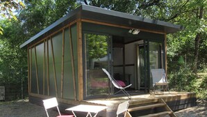 A small cabin with a glass door, a covered porch, and two folding chairs. - Cozy Mobile Home for 4 with Terrace (Tallard)