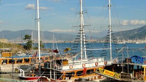 Un puerto con varios barcos, entre ellos un llamativo velero blanco con mástiles y aparejo.