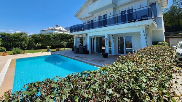 Una casa de dos pisos con piscina y balcón.