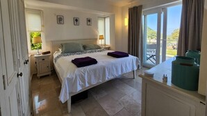 Un dormitorio con cama, mesitas de noche, cómoda y balcón con vistas.