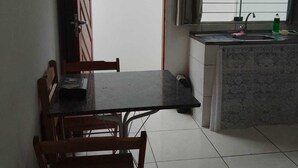A dining area with a table and chairs, a kitchen with a sink and window, and a door leading to another room. - casa/kitnet em São Jose na grande Florianópolis para ate 4 pessoas (São José)