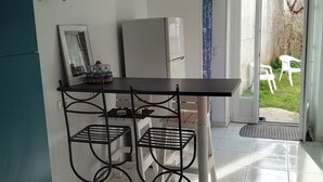 A kitchen with a refrigerator, a dining table with chairs, and a view of the outside. - Family home close to the sea (Penmarch)
