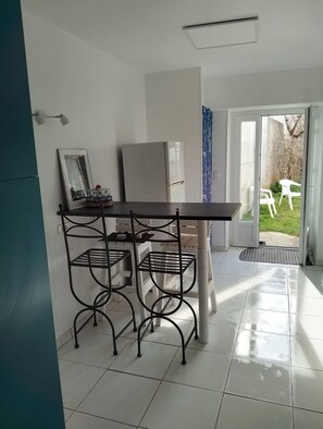 Eine Küche mit Kühlschrank, einem Esstisch mit Stühlen und Blick nach draußen.