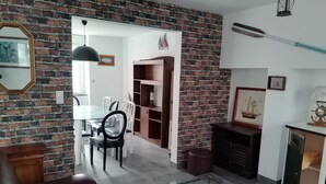 A living room with a brick wall, a glass coffee table, a leather sofa, and a fireplace. - Family home close to the sea (Penmarch)